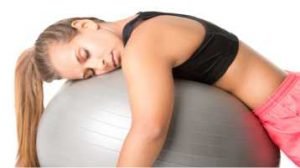 Overtraining, mulher jovem deitada exausta sobre a bola de pilates