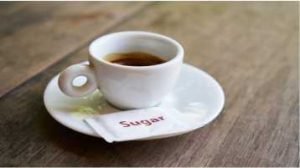 xícara de café com um sachê de açúcar no pires sobre mesa de madeira